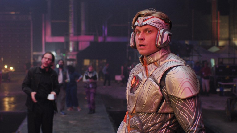 Billy Magnussen dressed in a silver superhero suit and helmet for HBO/Sky comedy The Franchise